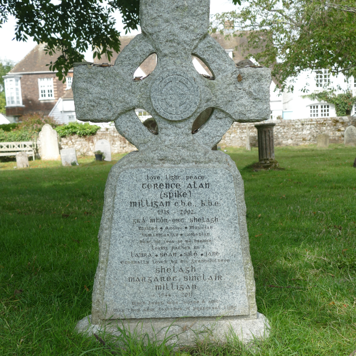 Gravestone of Spike Milligan at St Thomas the Martyr Church, Winchelsea, with carved stone cross in a churchyard